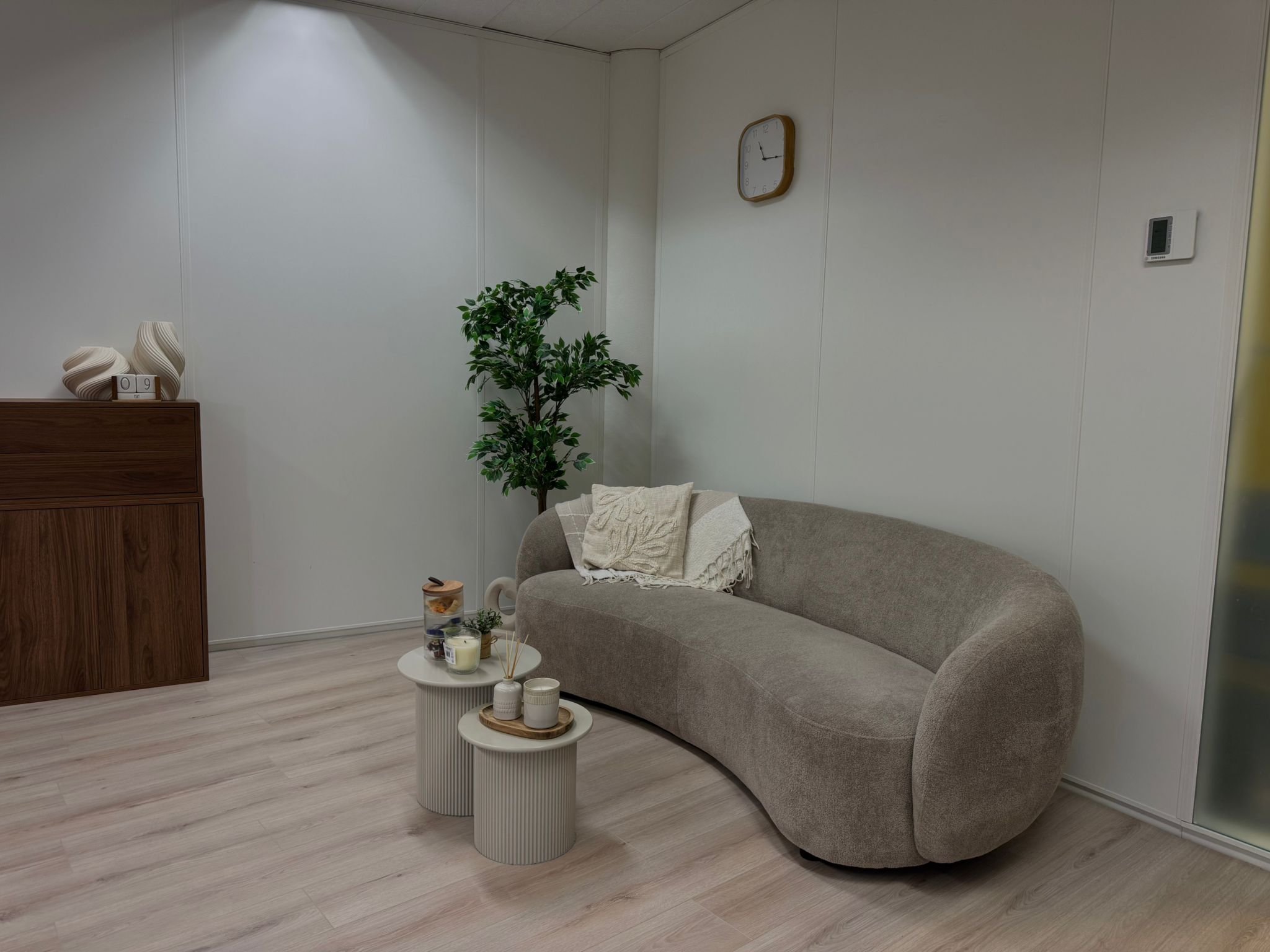 Zithoek in de studio met een ronde bank, bijzettafels en een plant